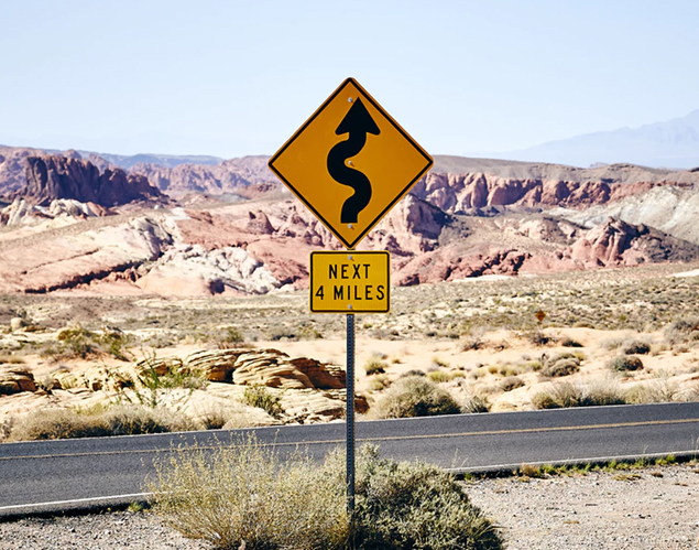Road sign near a highway in Nevada with backdrop of natural rock formations