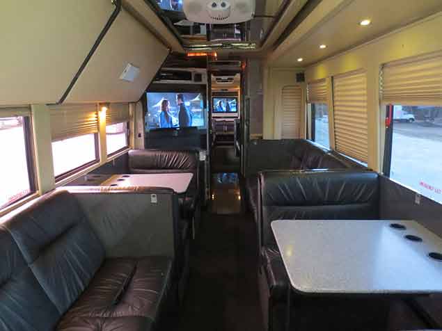 Interior of a Windstar Charter bus with tv, couches, and tables